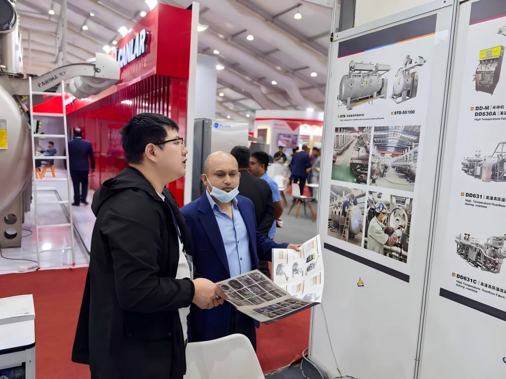 Visitor discussing dyeing machine posters at DTG Bangladesh 2025